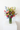 Bouquet of colorful flowers in a clear vase on a white surface with a white background